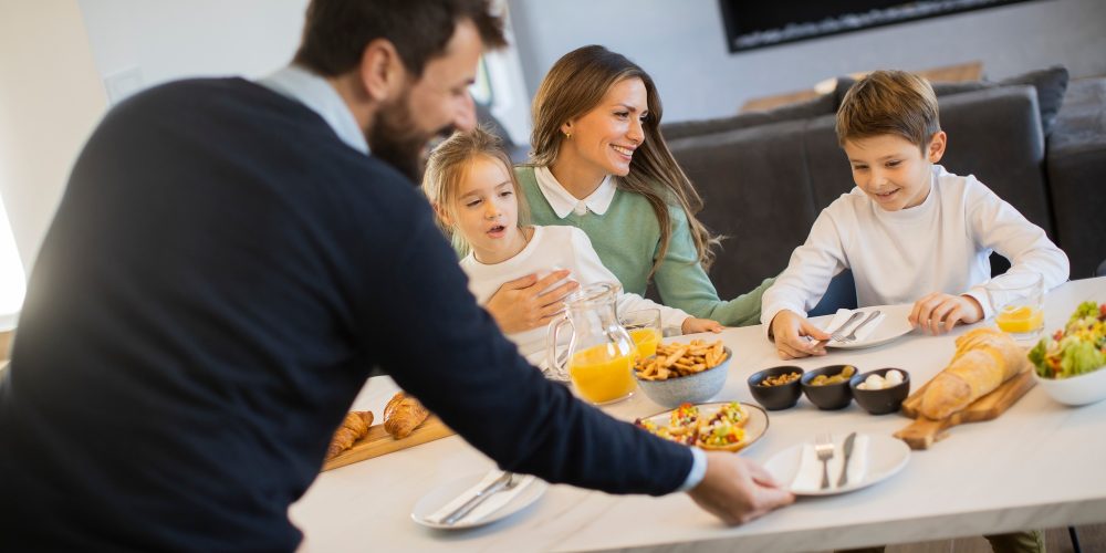 Young happy family talking while having breakfast at dining table